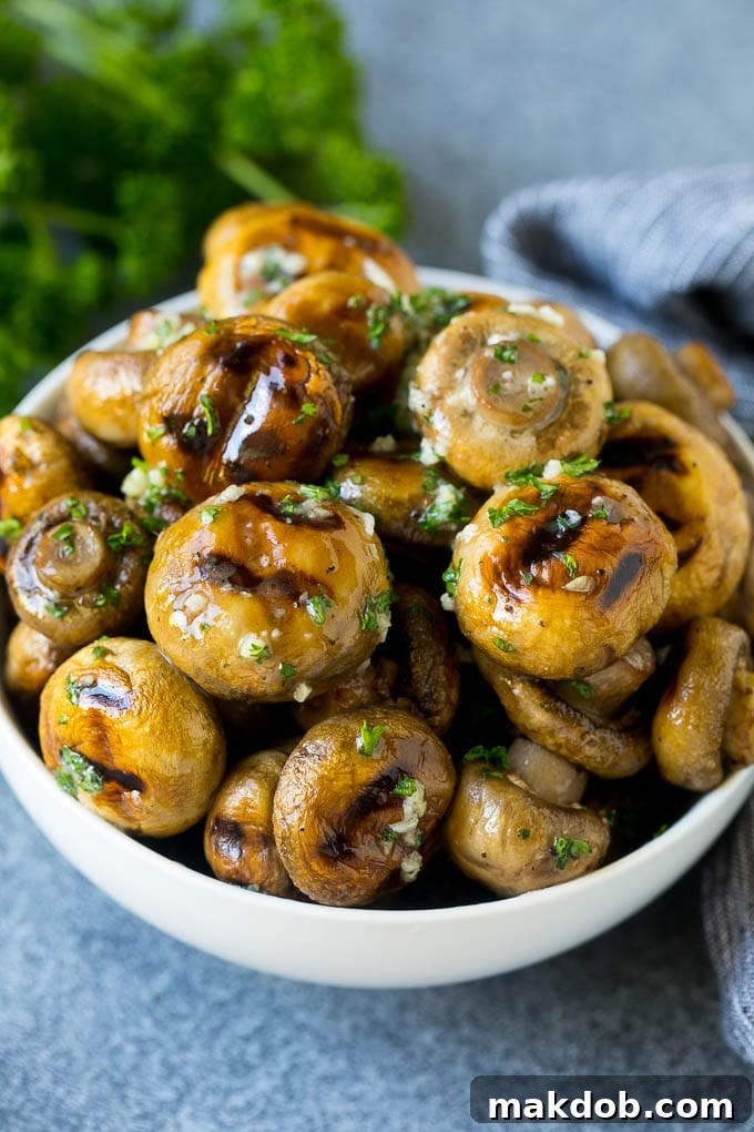 Grilled Mushrooms Recipe | Mushroom Kabobs | Mushroom Side Dish #mushroom #grilling #garlic #keto #lowcarb #dinneratthezoo Grilled mushrooms coated with garlic butter in a serving bowl, showcasing their golden-brown color and tender texture.