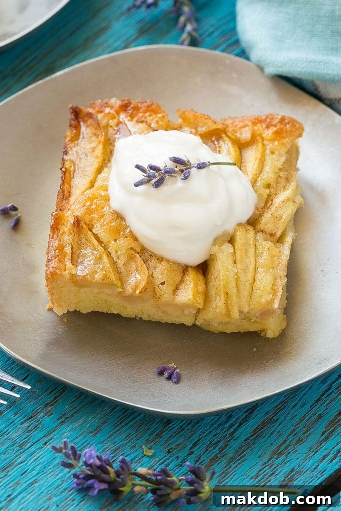 Spiced Apple Comfort Cake 6 A mouth-watering slice of apple cinnamon cake presented on a small plate, adorned with a generous topping of whipped cream.