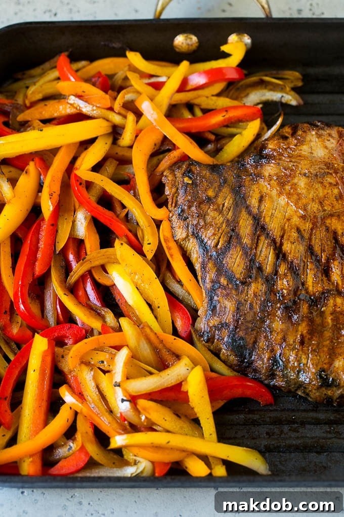 Marinated flank steak and thinly sliced bell peppers ready for grilling on a grill pan.