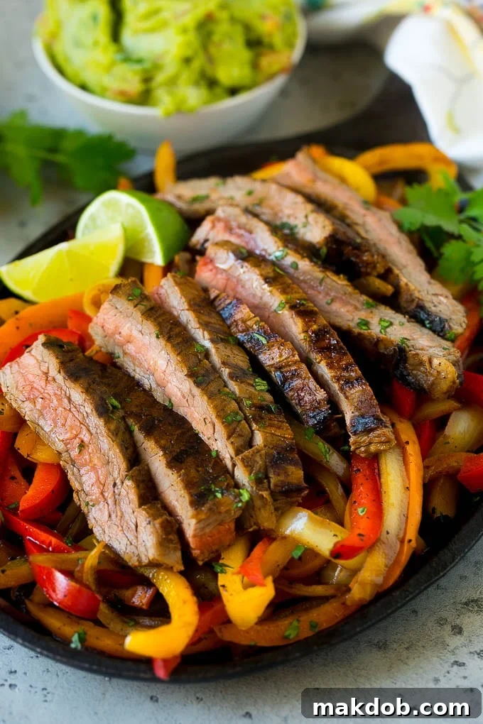 A sizzling skillet of steak fajitas with vibrant red and yellow bell peppers and onions.