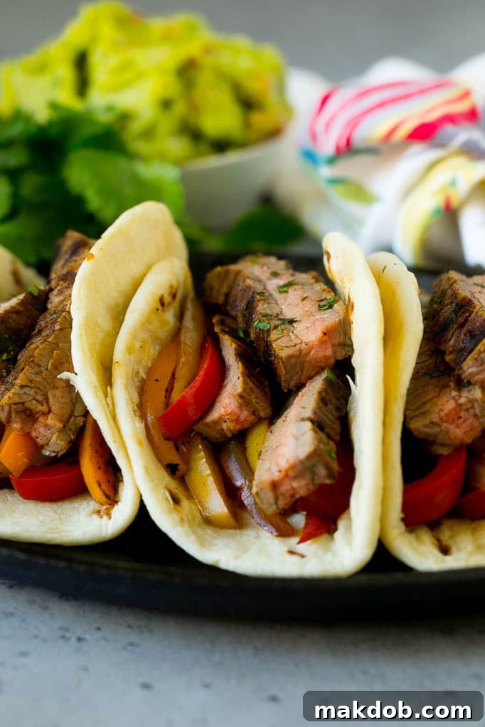 Soft tortillas overflowing with thinly sliced steak, colorful sauteed peppers, and onions.