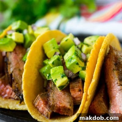 Steak tacos topped with avocado, red onion and cilantro.