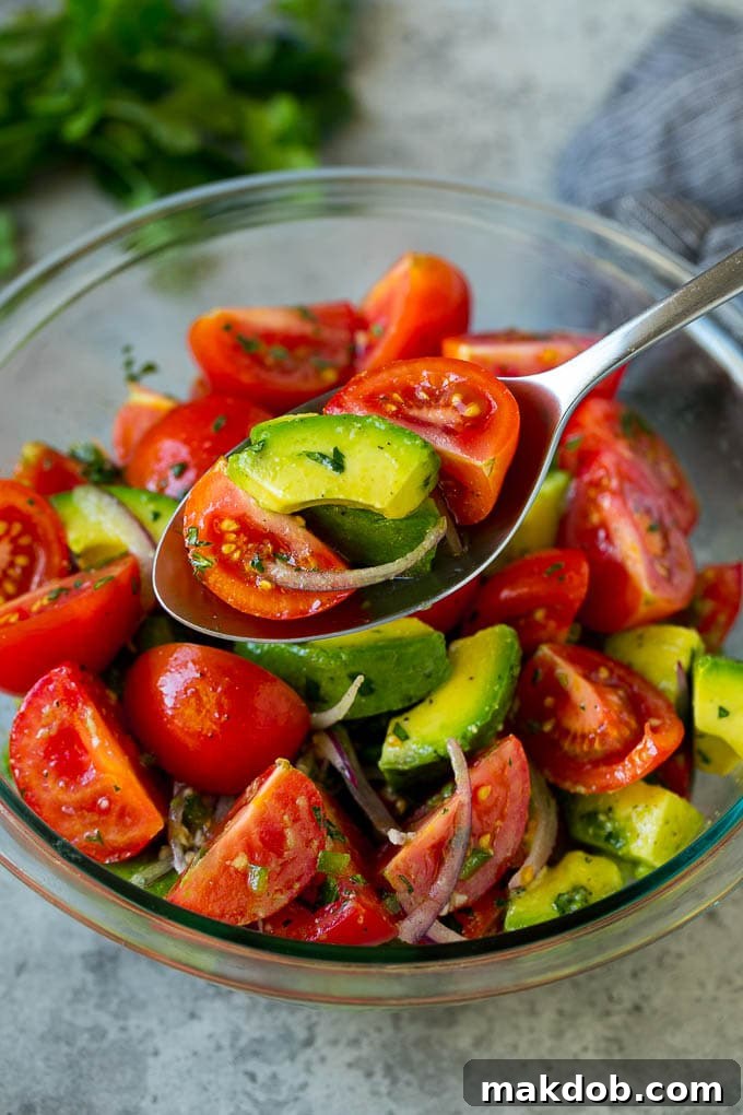 Serving Tomato Avocado Salad | Fresh & Flavorful Dish | Healthy Side A serving spoon lifting a spoonful of the refreshing Tomato Avocado Salad, showcasing the perfectly coated veggies and zesty lime dressing.