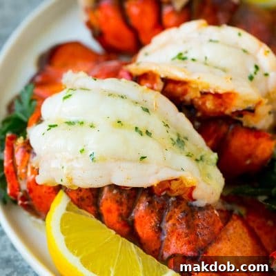 Broiled lobster tails topped with garlic butter, ready for plating.
