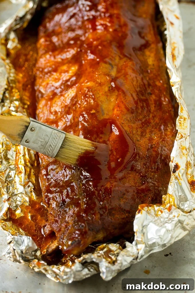 A brush basting smoked ribs with delicious BBQ sauce, creating a glossy finish.