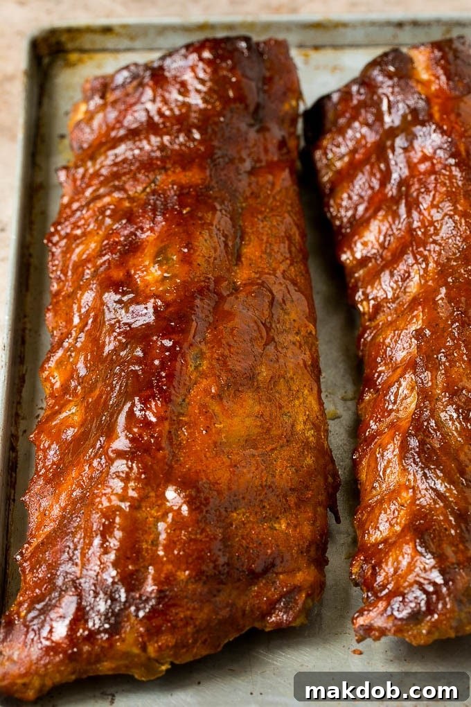 Racks of perfectly smoked ribs, glistening with BBQ sauce, ready to be carved.