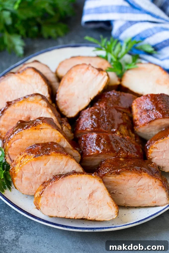 Smoked pork tenderloin sliced on a serving plate, showcasing its tender, juicy interior.