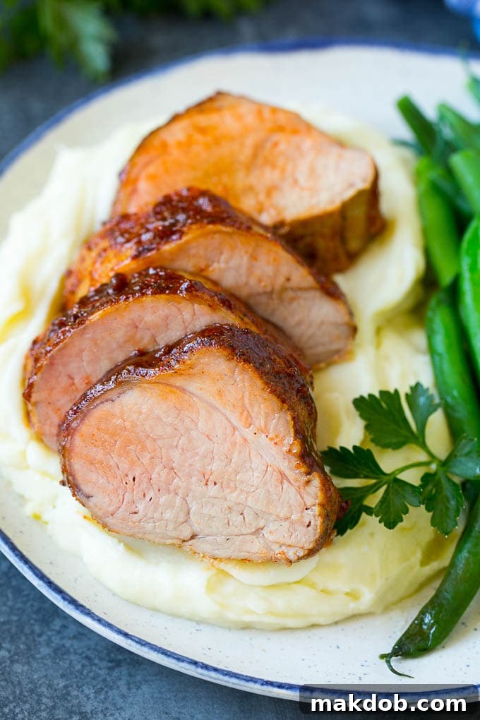 Sliced smoked pork tenderloin served with creamy mashed potatoes and vibrant green vegetables.