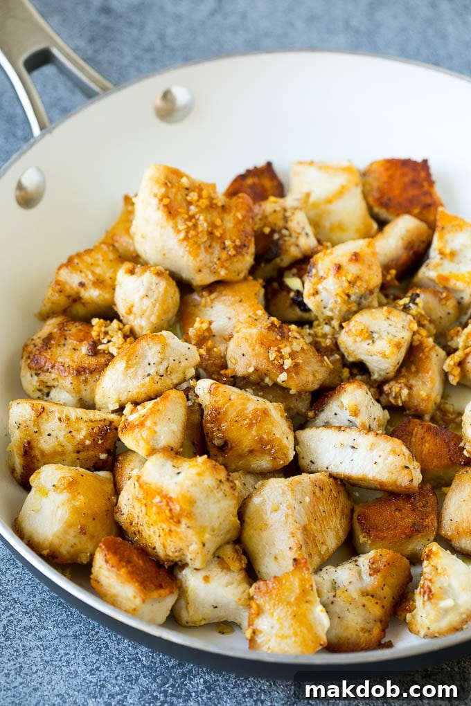 Golden-brown seared chicken pieces and minced garlic sizzling in a skillet.