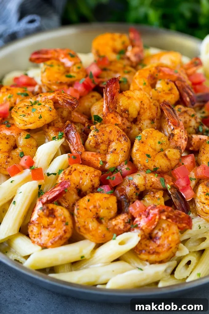A pan of Cajun shrimp pasta garnished with tomatoes and herbs.