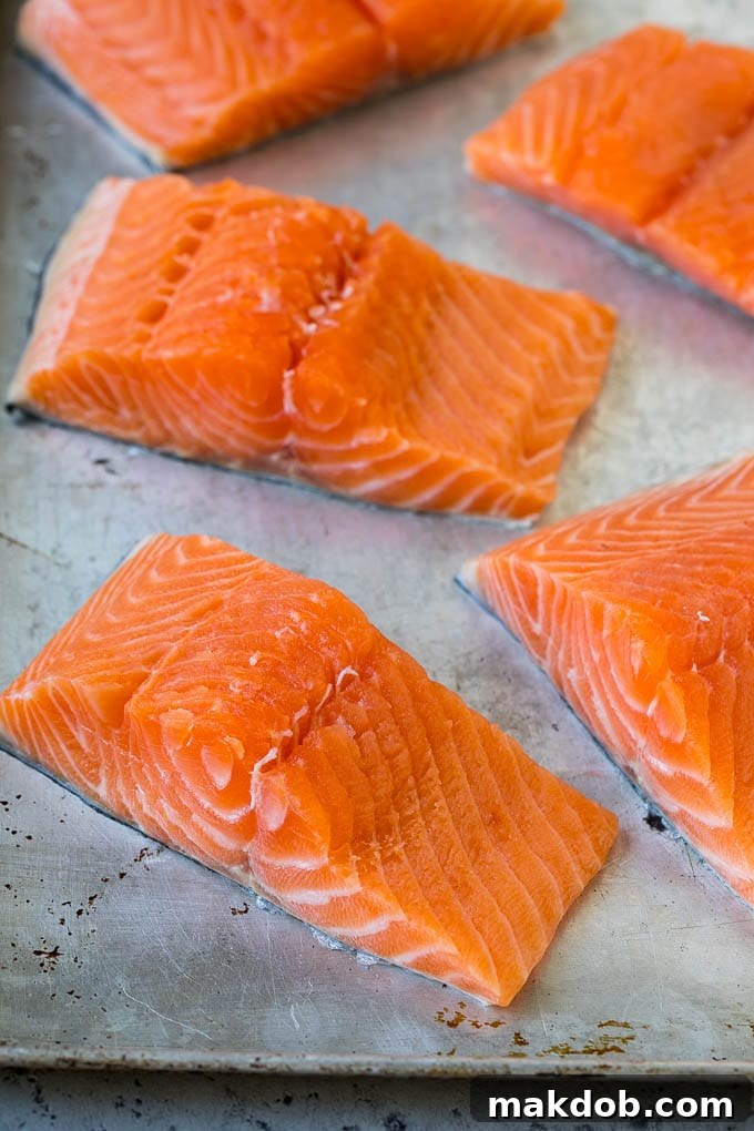 Raw salmon fillets arranged on a sheet pan, ready for seasoning.