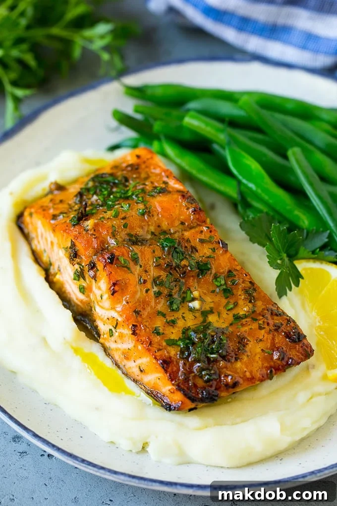 A delicious roasted salmon fillet served elegantly over a bed of creamy mashed potatoes, accompanied by vibrant green beans.