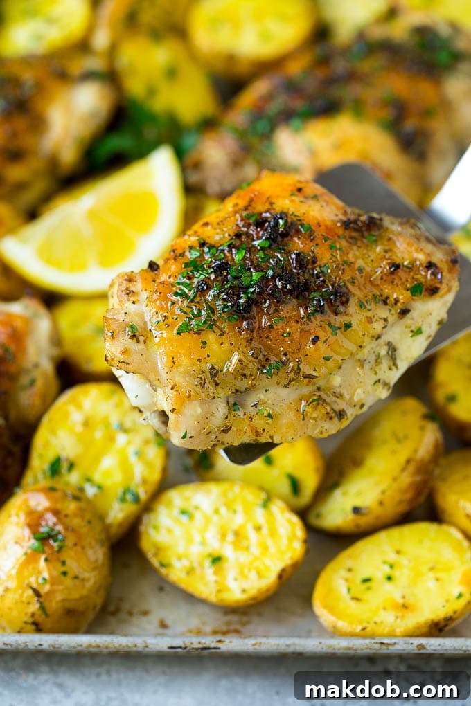 A spatula serving a piece of golden-brown Greek chicken thigh from the pan.