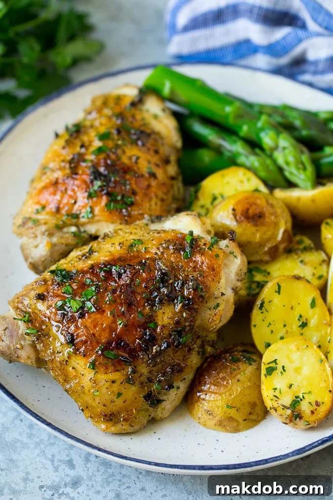 Greek chicken and potatoes beautifully plated with a side of fresh asparagus.