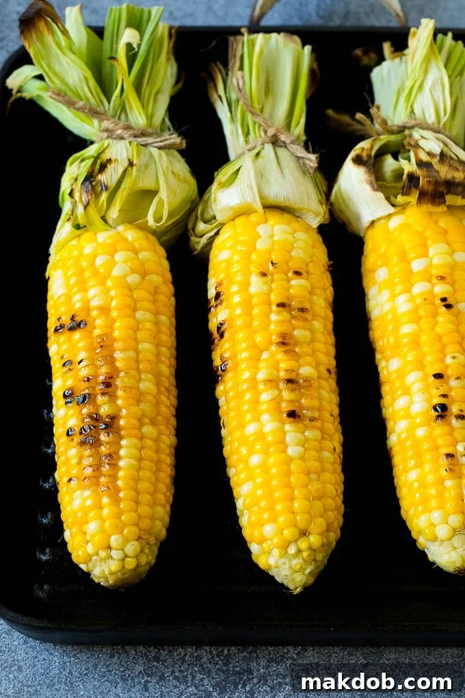 Corn cooking on a grill pan, showing slight char marks developing on the kernels.
