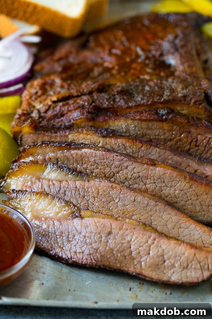 Beautifully sliced smoked brisket served with a side of homemade BBQ sauce, showcasing its tender texture.
