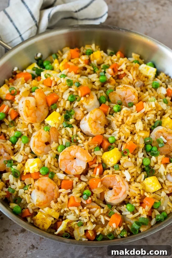 Shrimp Fried Rice Recipe | Chinese Fried Rice #rice #shrimp #peas #carrots #sidedish #dinner #dinneratthezoo A large pan filled with freshly made shrimp fried rice, featuring scrambled eggs, colorful vegetables, and plump shrimp, ready to be scooped.