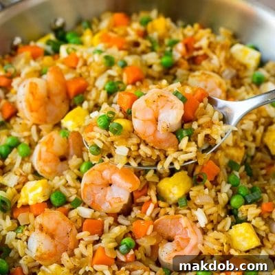 A serving spoon in a pan of shrimp fried rice, ideal for Pinterest sharing.