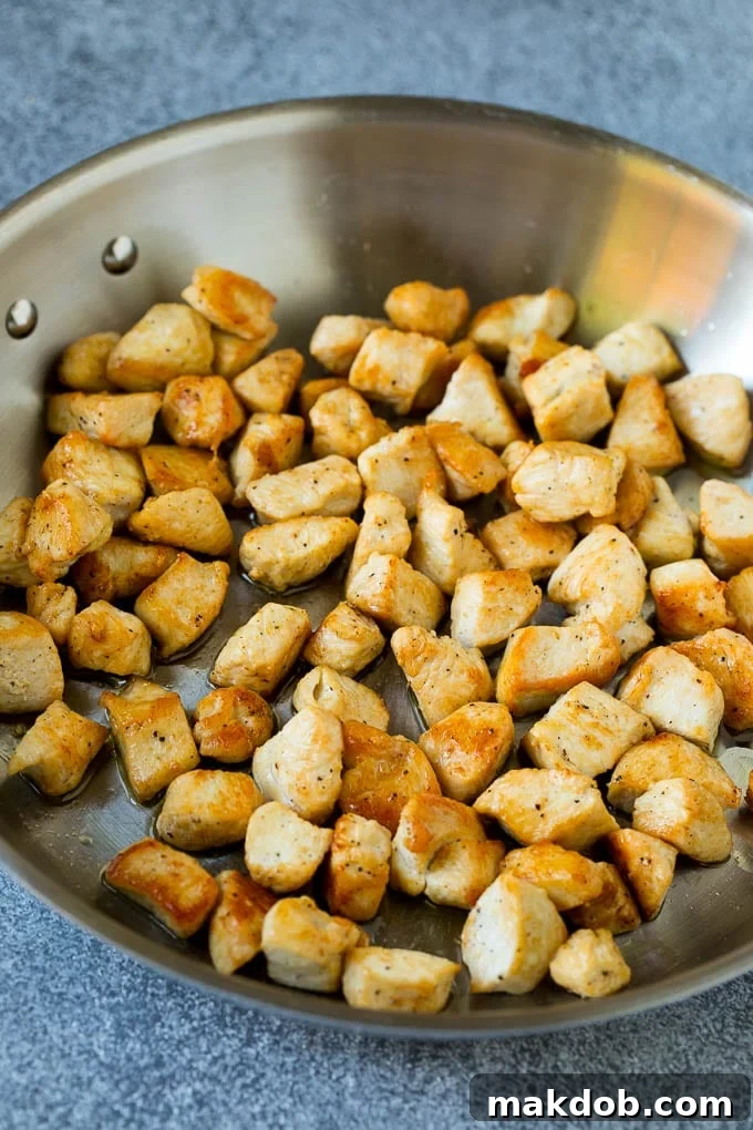 Cooked chicken pieces beautifully browned in a metal pan, ready to be combined with other ingredients for fried rice.