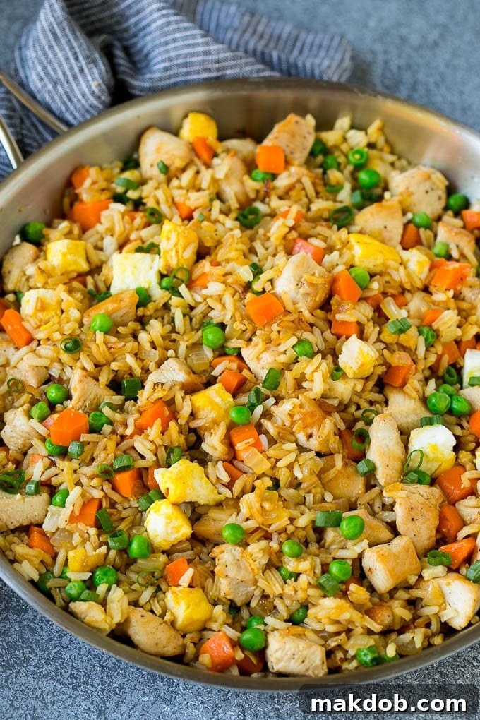 A large pan brimming with freshly prepared chicken fried rice, showing the beautiful mix of chicken, eggs, and colorful vegetables stir-fried to perfection.