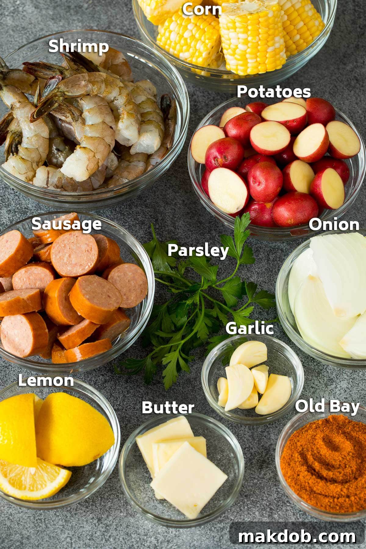 Ultimate Backyard Shrimp Boil 3 Bowls of ingredients including fresh shrimp, corn, potatoes, sausage, lemons, and seasonings laid out.