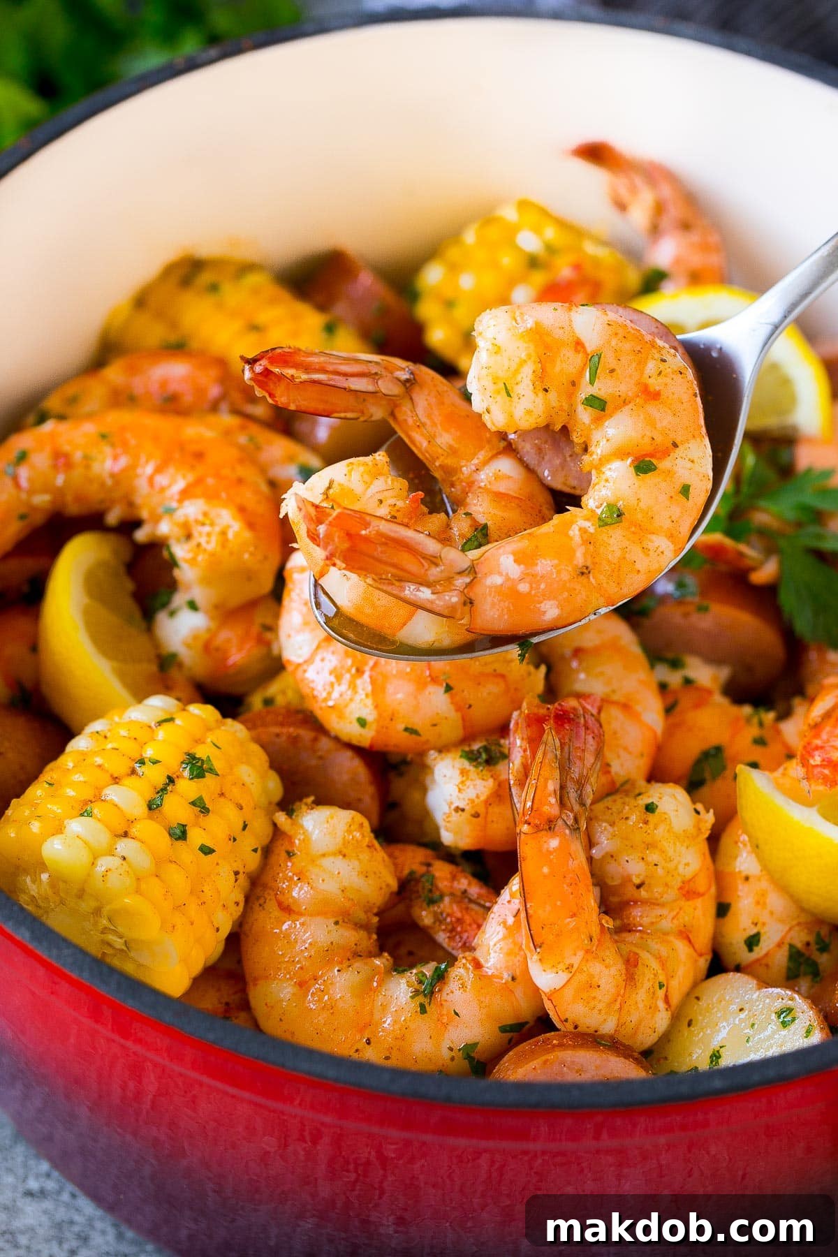 Ultimate Backyard Shrimp Boil 7 A spoon serving up a large, perfectly cooked shrimp from a shrimp boil.