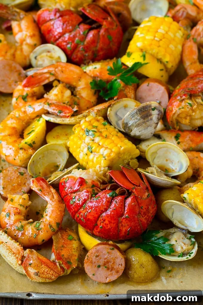 Seafood Boil Recipe | Shrimp Boil #lobster #shrimp #clams #crab #sausage #corn #potatoes #dinner #dinneratthezoo A sheet pan of seafood boil with shrimp, lobster tail, sausage, corn and potatoes.
