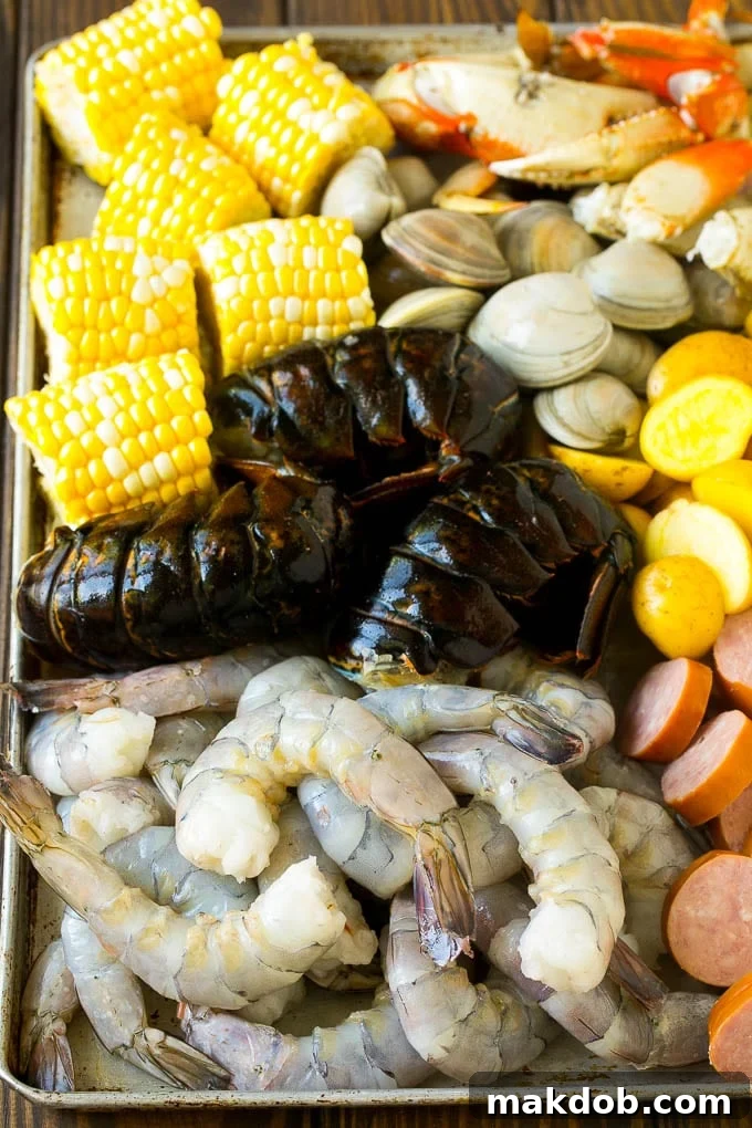 Seafood Boil Recipe | Shrimp Boil #lobster #shrimp #clams #crab #sausage #corn #potatoes #dinner #dinneratthezoo Raw shrimp, lobster, sausage, corn, clams and potatoes on a sheet pan.
