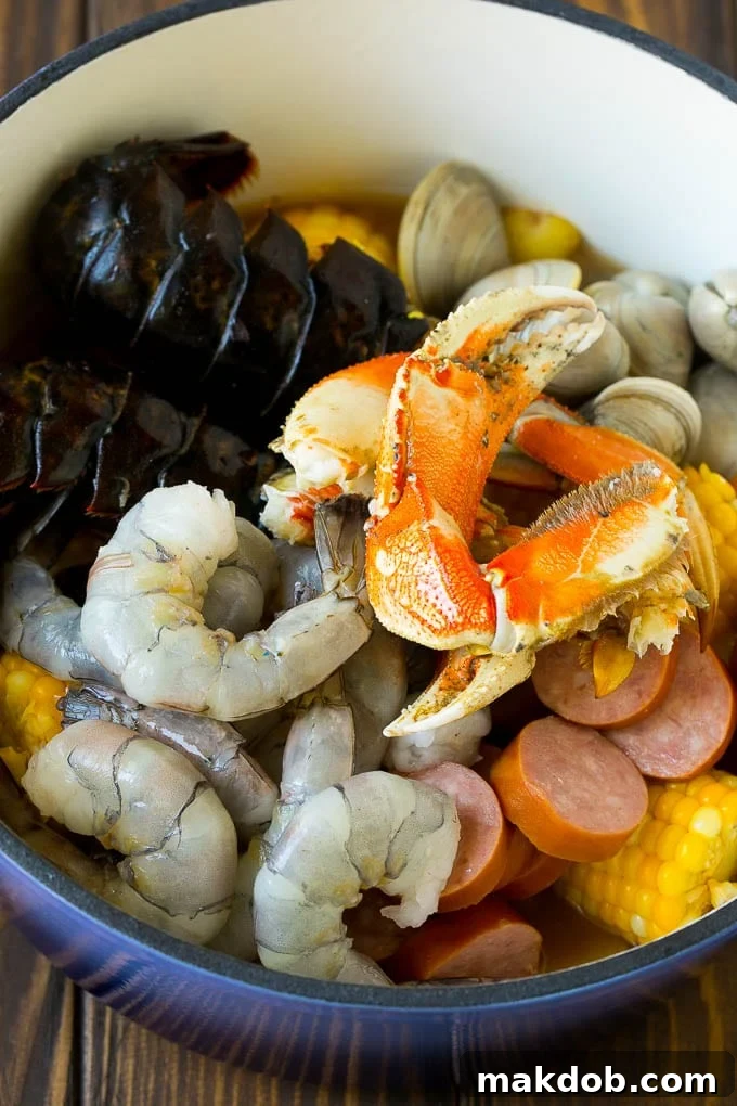 Seafood Boil Recipe | Shrimp Boil #lobster #shrimp #clams #crab #sausage #corn #potatoes #dinner #dinneratthezoo A pot filled with assorted seafood, corn and sausage.