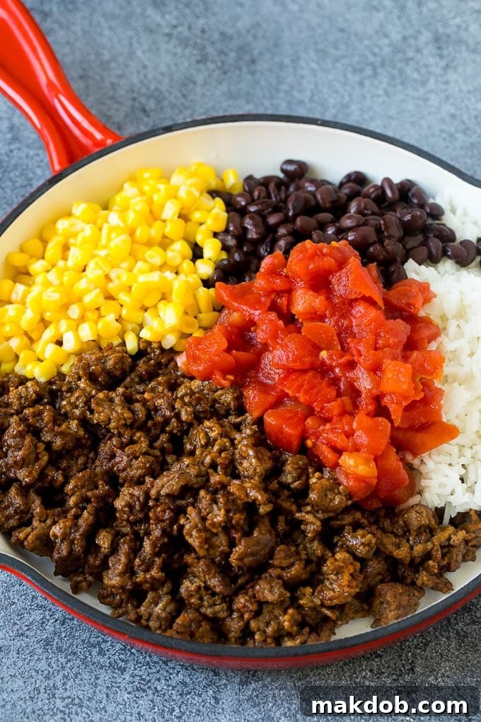 A skillet filled with ground beef, rice, tomatoes, beans and corn.