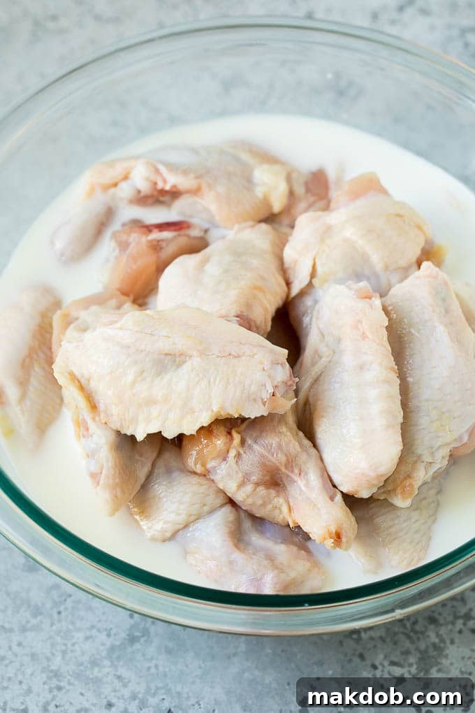 Buttermilk Marinated Chicken Wings Chicken wings soaking in a bowl of creamy buttermilk marinade, preparing for frying.