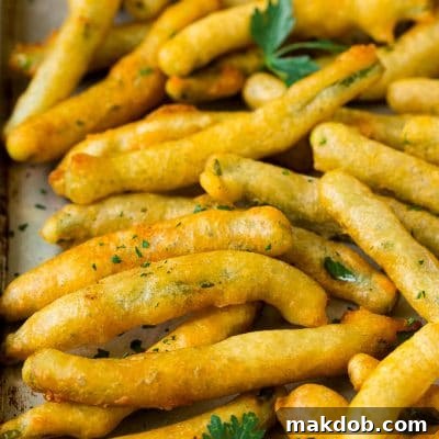 A sheet pan of fried green beans garnished with chopped parsley.