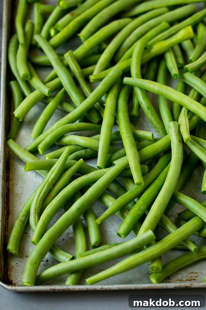 Fresh green beans arranged neatly on a sheet pan, ready for preparation.