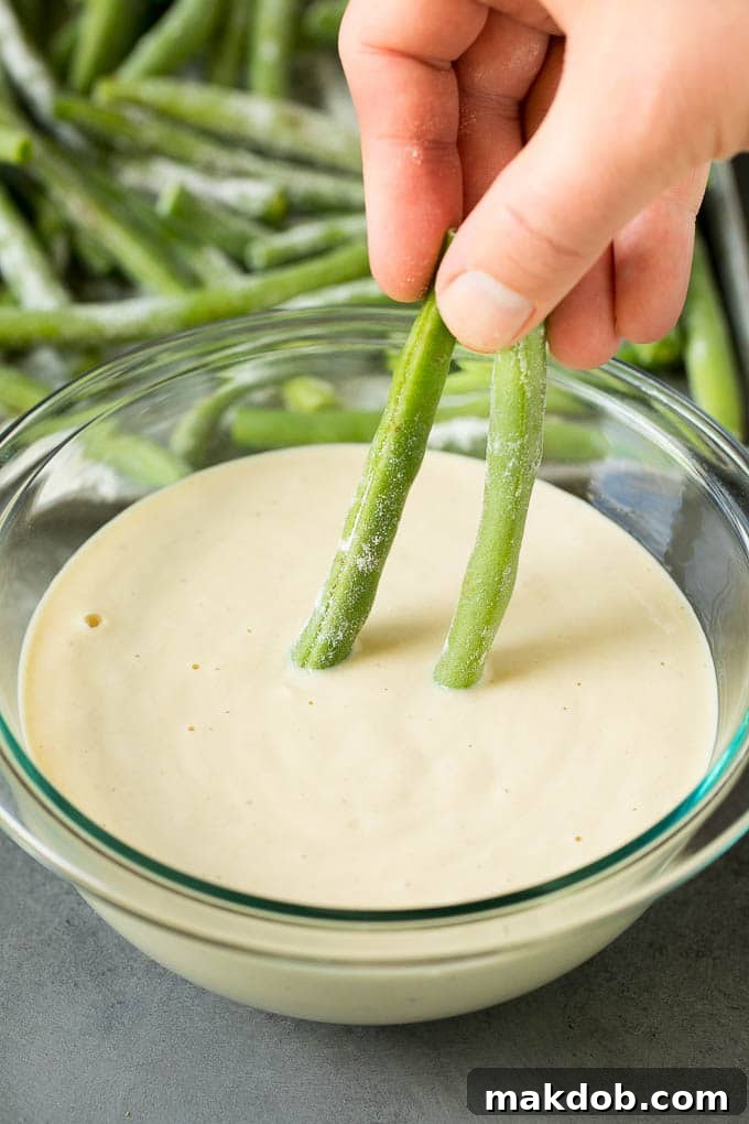 Fried Green Beans Recipe | Green Beans #greenbeans #appetizer #snack #dinneratthezoo A hand dipping beans into beer batter.