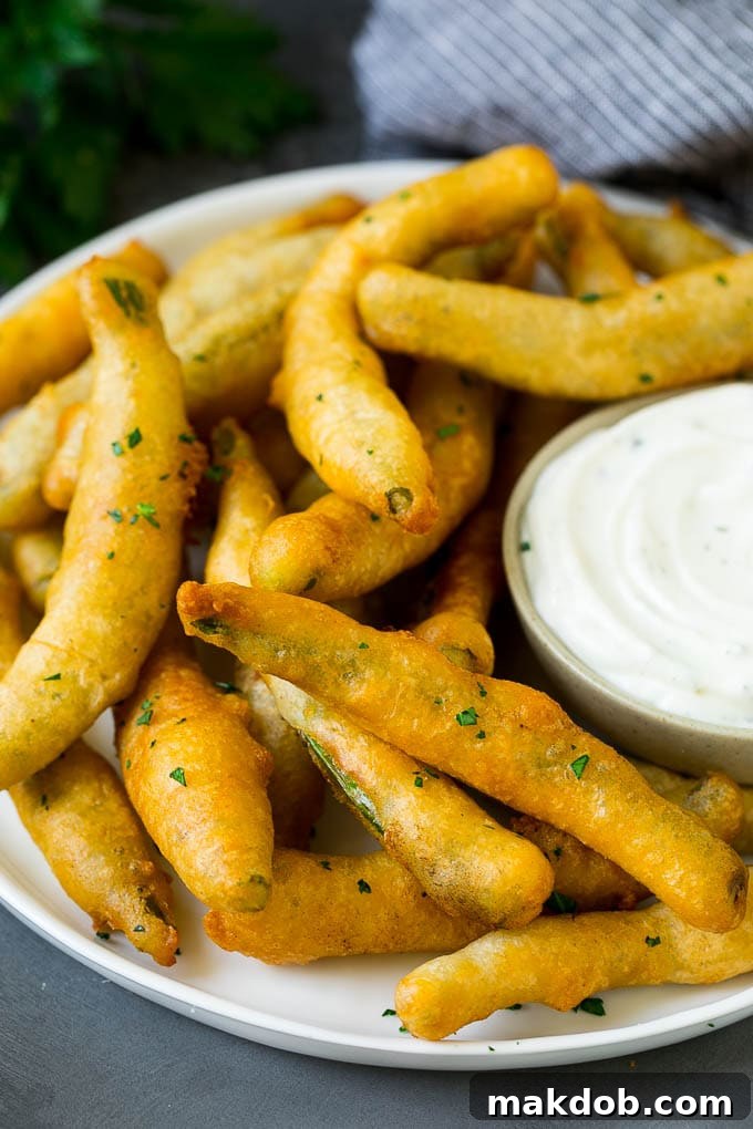 A beautifully arranged plate of golden fried green beans, served with a side of creamy ranch dip, ready to be enjoyed.