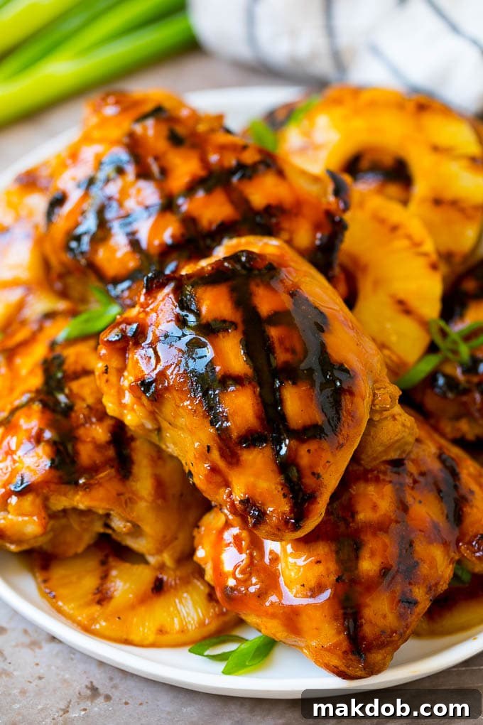 A vibrant plate of grilled Huli Huli chicken and pineapple, garnished with green onions, ready for a delicious meal.