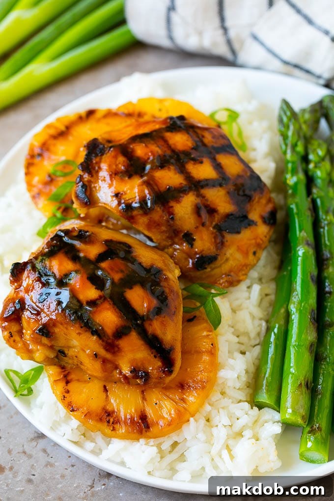 Huli Huli chicken and grilled pineapple served over a bed of fluffy white rice, garnished with fresh green onions for a complete meal.