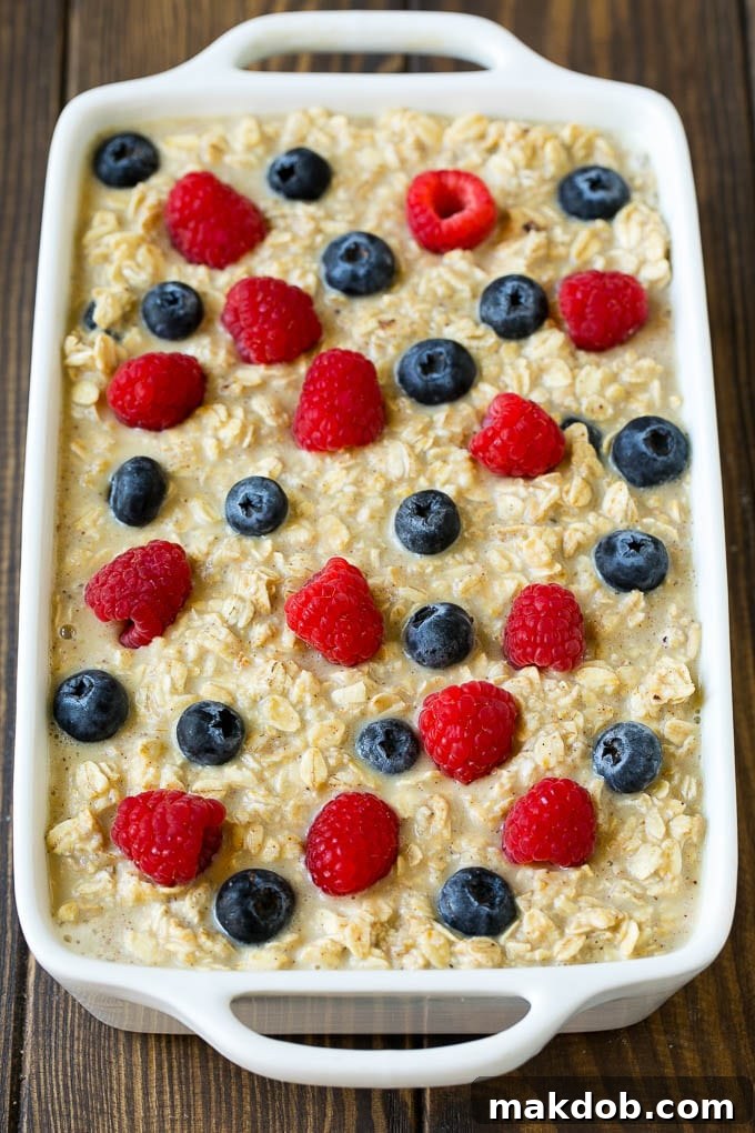 Baked Oatmeal Recipe | Meal Prep | Healthy Oatmeal #oatmeal #casserole #breakfast #brunch #dinneratthezoo #mealprep Oatmeal poured into a baking dish with berries on top.