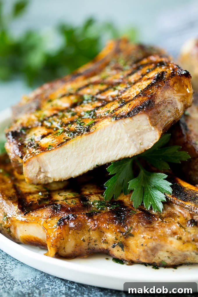 Juicy Grilled Pork Chops A stack of perfectly grilled pork chops, with one chop cut open to reveal its juicy interior.