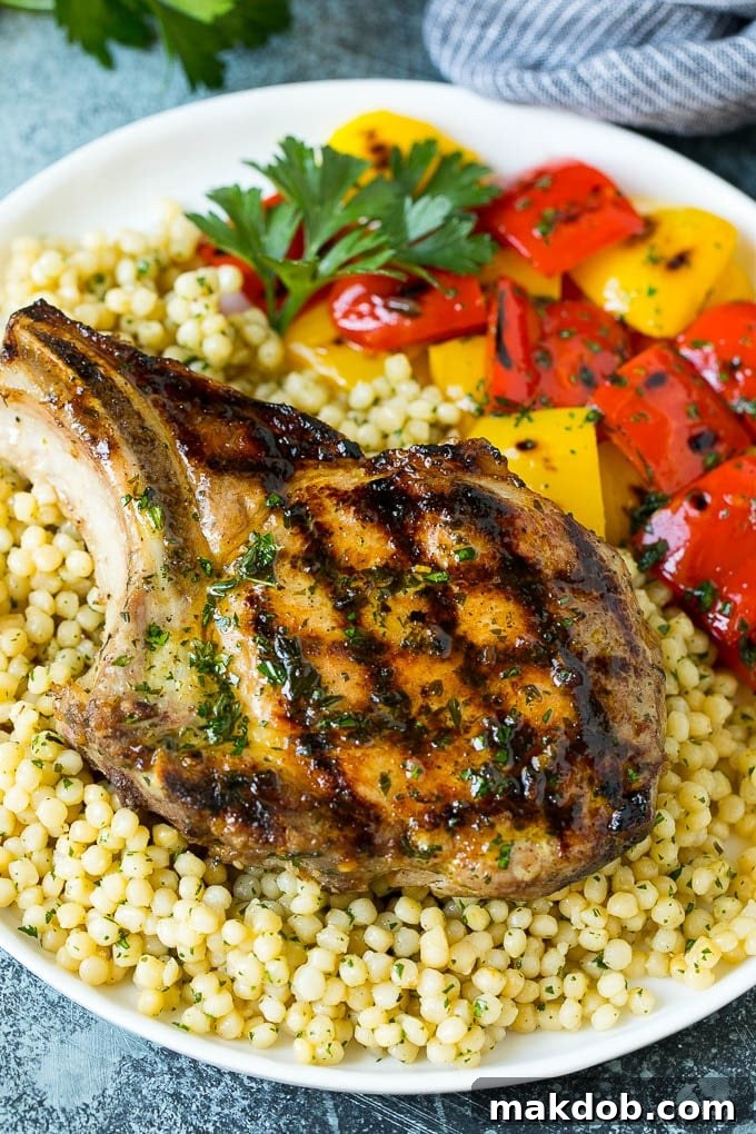 Grilled Pork Chop with Sides A beautifully plated grilled pork chop, served over couscous with vibrant bell peppers on the side.