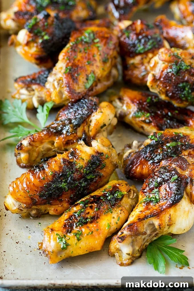 Grilled chicken wings arranged neatly on a sheet pan, garnished with fresh parsley.