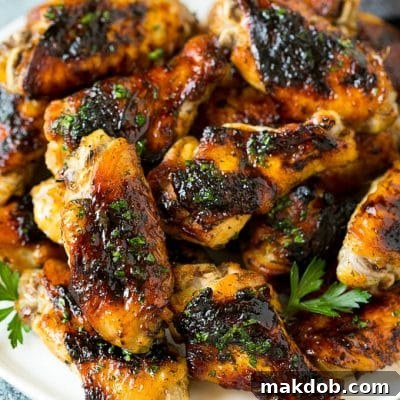 A plate of grilled chicken wings coated in herbs.