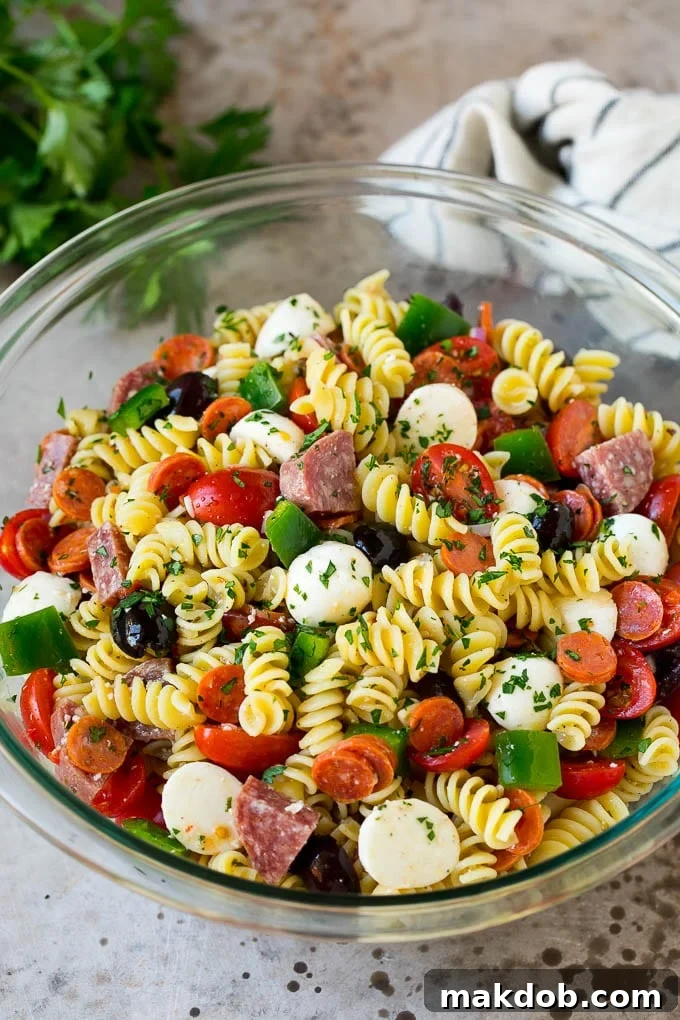 A large bowl of Italian pasta salad, generously loaded with a mix of savory meats, cheeses, and colorful vegetables, highlighting its hearty and inviting appeal.