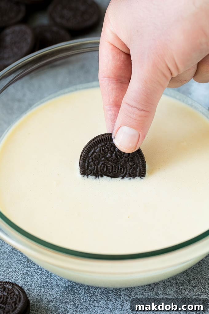 An Oreo cookie being dipped into a bowl of batter.