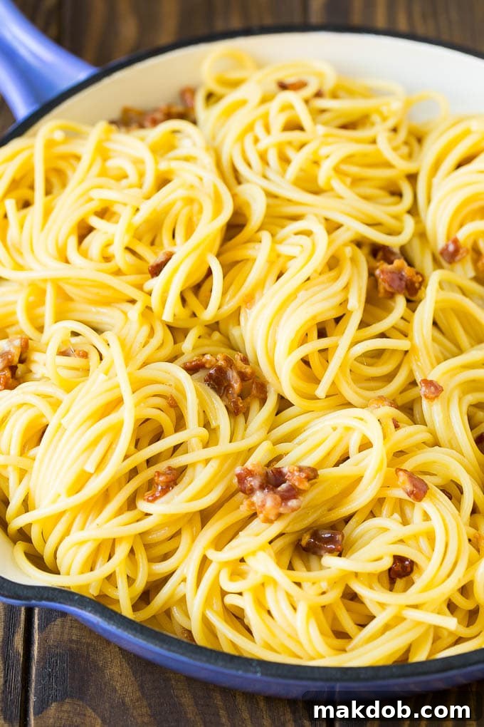 Spaghetti with crispy bacon in a creamy egg and cheese sauce, garnished with parsley.