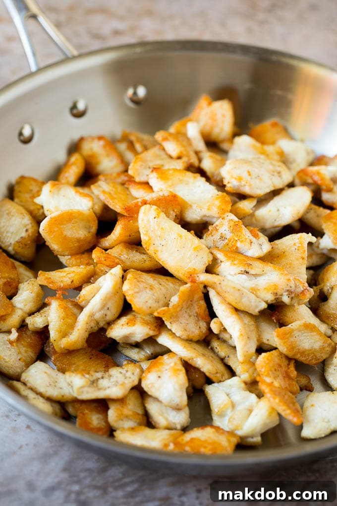 Thinly sliced chicken seared in a skillet.