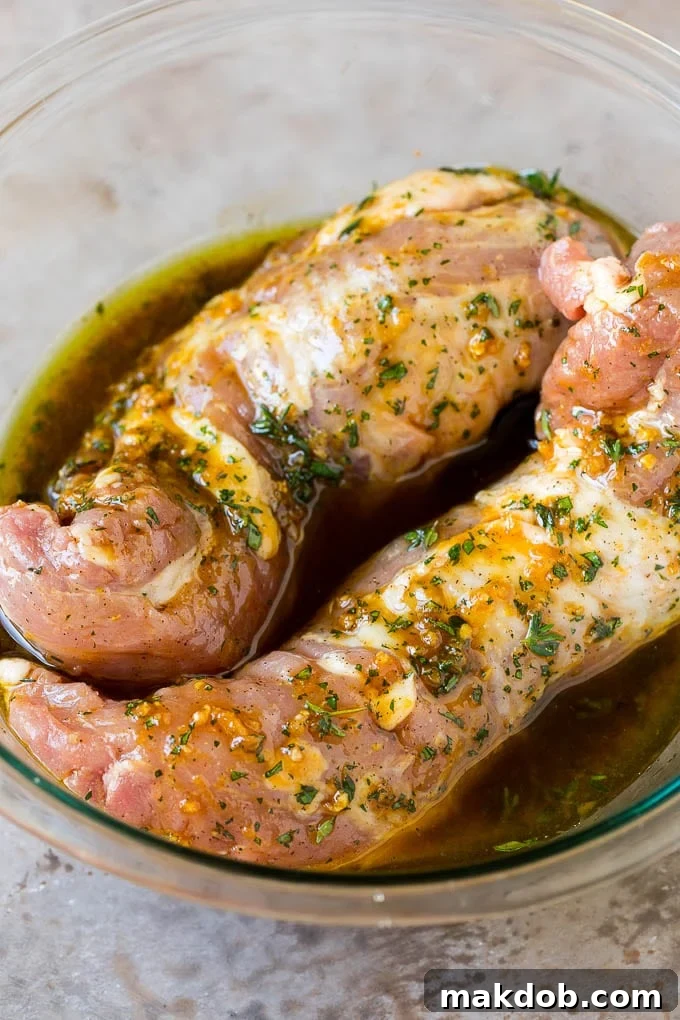 Pork tenderloin in a bowl of marinade.