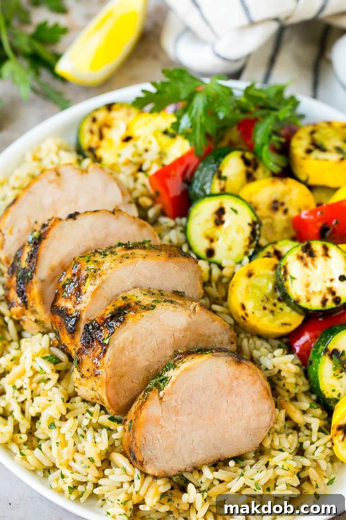 Sliced pork tenderloin on a plate of couscous with vegetables.