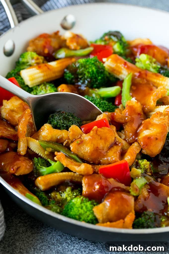 A spoon serving up a portion of spicy chicken stir fry.