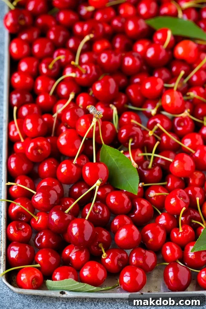 Cherry Pie Filling Recipe #pie #cherries #dessert #sweets #dinneratthezoo #summer Fresh, vibrant cherries spread out on a sheet pan, ready for preparation.